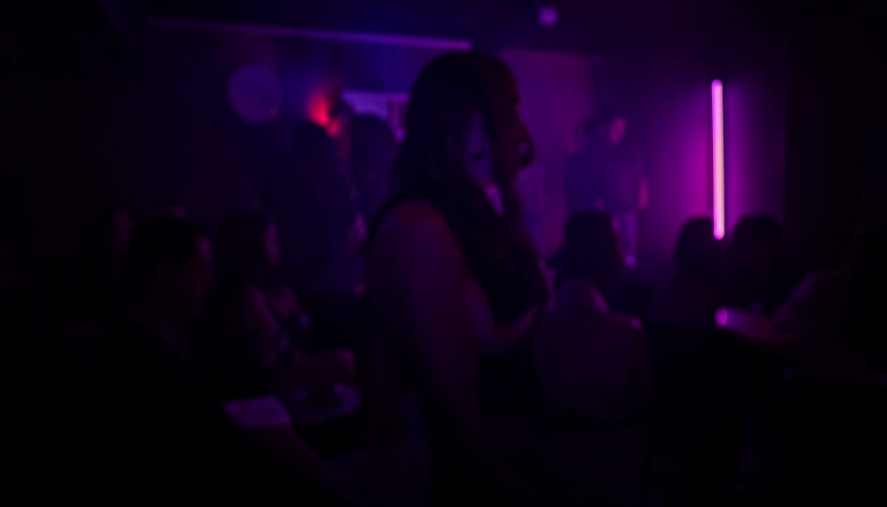 Dark atmospheric background with deep purple and magenta neon glow, moody adult entertainment ambiance